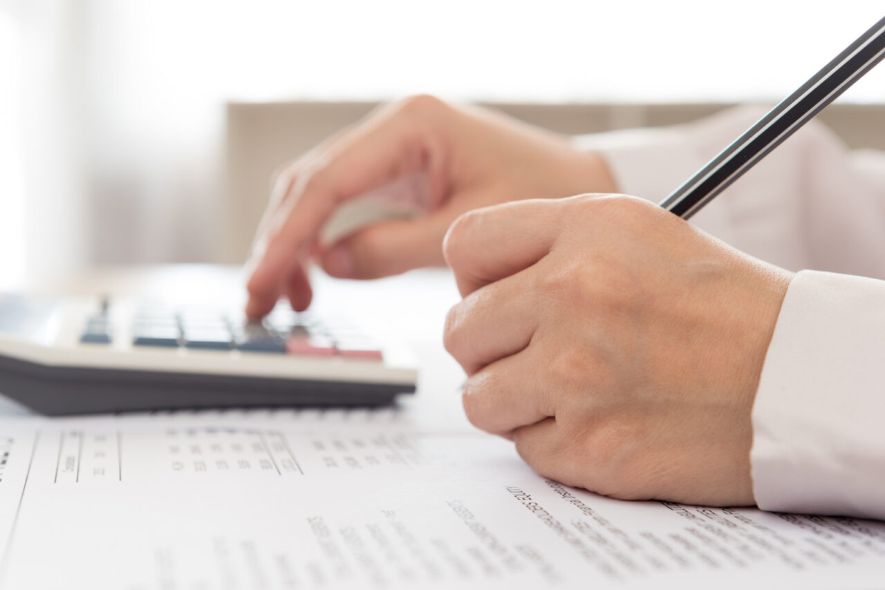 What Does Bookkeeper Do - A hand working on a calculator and paper